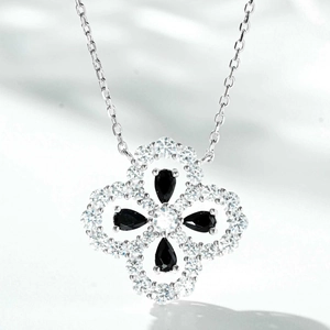Macro detail of silver four-leaf clover pendant with black stones and micro-pave crystals
