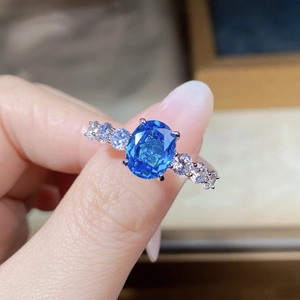 Macro shot of oval blue sapphire ring with sparkling side zircons in 925 silver setting