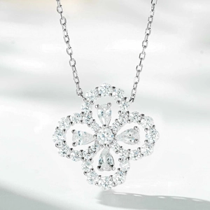 Macro detail of silver four-leaf clover pendant with pink diamonds and floral accents