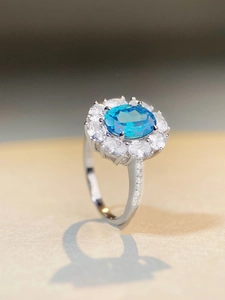 Macro shot of oval aquamarine silver ring with halo crystals and sparkling side diamonds
