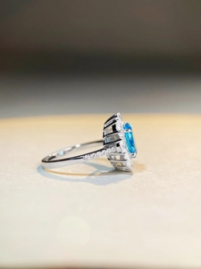 Macro side view of silver ring with oval aquamarine gemstone and diamond pavé details