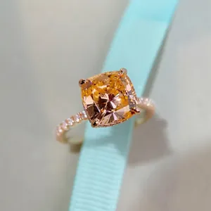 Luxurious cushion-cut orange gemstone ring with pavé diamond band on blue ribbon