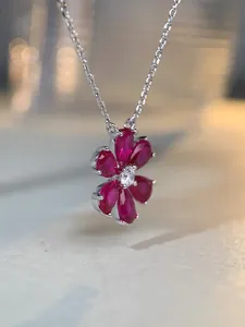 Gros plan du pendentif camélia avec pétales rouges en forme de poire et chaîne argent