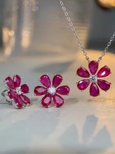 Gros plan sur l'ensemble bijoux camélia en argent avec pierres rouges et centre brillant