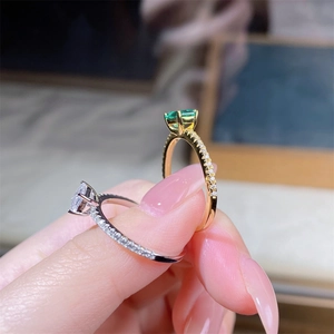 Close-up of square cut green and white crystal rings with four-prong settings and pave band