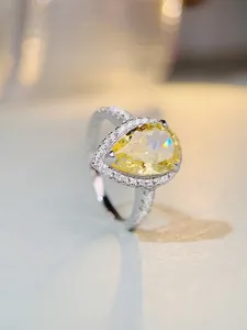 Macro detail of pear cut yellow gemstone ring with halo diamonds in s925 silver