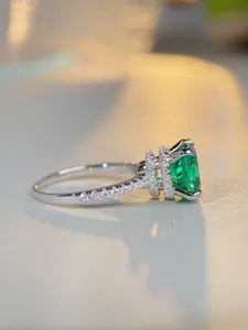 Vue latérale macro d'une bague avec émeraude verte et anneau en argent serti de diamants