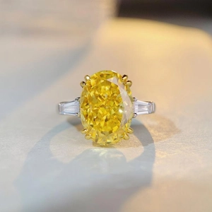 Macro shot of oval cut yellow gemstone with six-prong setting and side baguette diamonds