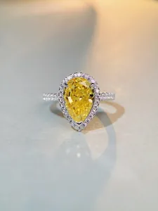 Macro shot of a pear-cut yellow diamond ring with halo setting and sparkling pavé accents