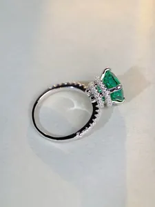 Détail macro d'une bague avec gemme verte taille émeraude et anneau argenté pavé
