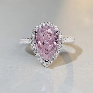 Macro shot of a pear-cut pink gemstone ring with sparkling halo and silver band