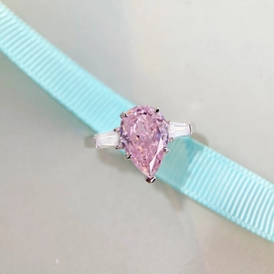 Macro view of pear-cut pink gemstone ring with side trapezoid diamonds and 925 silver band
