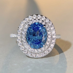 Oval blue gemstone ring with double-layer diamond halo on a polished silver band