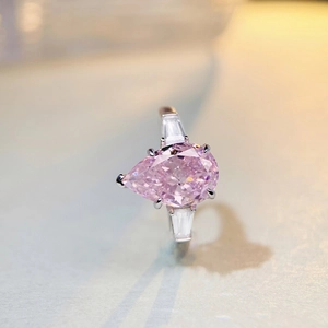 Macro detail of pear-cut pink gemstone ring with tapered baguette side stones