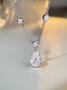 Macro shot of pear-cut zircon pendant with tiny round stones on a silver chain