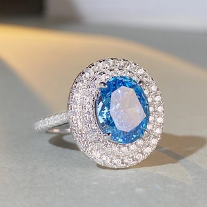 Macro shot of large oval blue sapphire with double diamond halo and pavé silver band