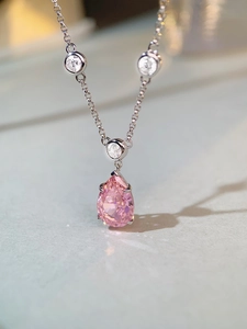 Macro shot of S925 silver necklace with pear-shaped pink gemstone and three round zircons