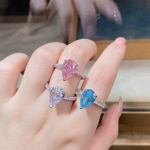 Macro detail of pear-cut pink and blue carbon diamond rings with pavé setting