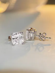 Macro shot of Asscher cut square diamond stud earrings in a classic four-prong silver setting
