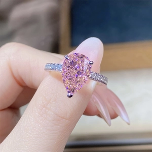 Macro shot of a pear-cut pink zircon ring with a diamond-encrusted silver band