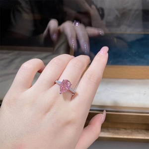 Detailed view of pear-cut pink high-carbon diamond ring on hand with pavé band
