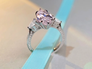 Macro shot of 7-carat pink oval zircon ring with pear-shaped side stones and pavé band