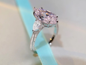 Macro detail of marquise pink stone ring with side teardrop zircon on blue ribbon