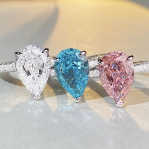 Macro detail of three pear-cut stones in blue, pink, and white on a pavé-set silver ring