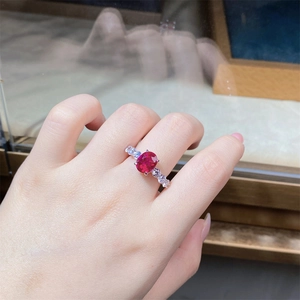 On-hand display of a S925 silver ring featuring an oval red ruby and sparkling zircon side stones