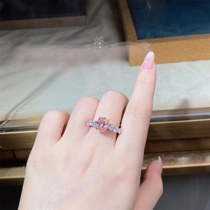 Close-up of an oval champagne pink gemstone ring with round side diamonds on a silver band