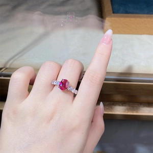Close-up of a sterling silver ring with a large oval red ruby and diamond side stones