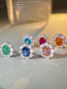 Macro shot of silver studs with oval rubies and colorful gems in halo diamond setting