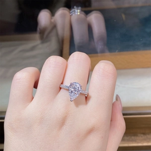 Macro view of pear-cut high carbon diamond ring with silver band on finger