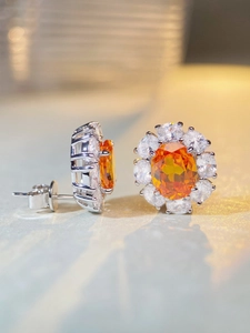 Macro detail of S925 sterling silver stud earrings featuring oval orange zircon stones