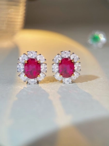 Vue macro de boucles d'oreilles rubis ovales avec halo de zircons et monture argent S925