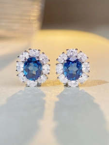 Macro detail of oval blue gemstone stud earrings with halo micro-pave setting