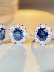 Macro shot of silver ring featuring an oval blue gemstone with a diamond halo setting