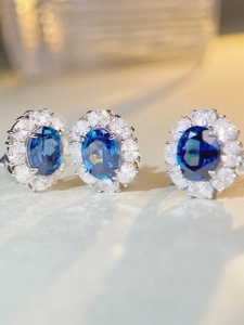 Macro detail of oval-cut blue sapphire silver earrings with sparkling halo diamond setting