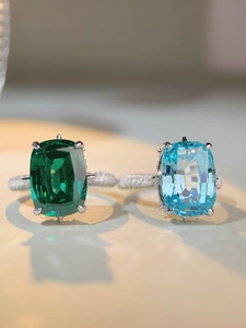 Makroaufnahme von Smaragd- und Aquamarinringen mit mikropavé besetzten Bändern