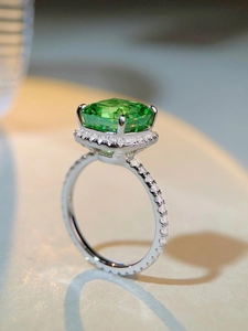 Vue latérale macro d'une bague avec pierre précieuse vert émeraude et halo de diamants