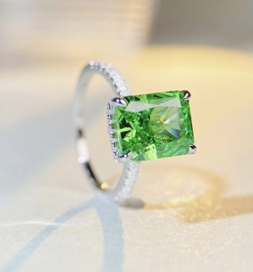 Detail of emerald-cut green gemstone ring with side pave diamonds in silver setting