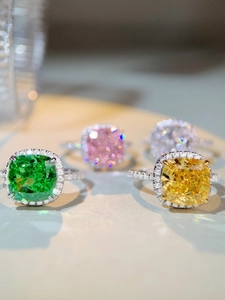 Vue macro de bagues halo avec moissanite taille coussin verte, jaune, rose et blanche