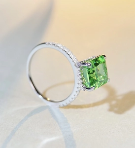 Macro detail of emerald-cut green gemstone ring with pavé diamond band in s925 silver