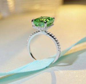 Macro shot of emerald-cut green gemstone ring with white cubic zirconia pavé detailing