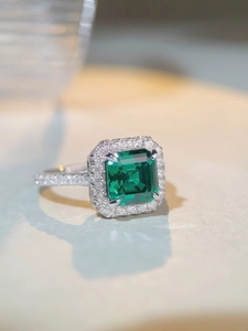 Macro shot of emerald cut green gemstone ring with pavé diamonds in silver setting
