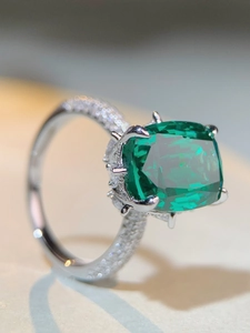 Vista macro di una gemma verde taglio smeraldo con incastonatura a sei griffe su argento