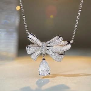 Detailed close-up of a silver bow necklace featuring a sparkling pear-cut diamond pendant