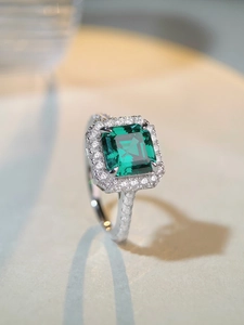 Detailed macro view of S925 silver halo ring with emerald cut green gemstone and pavé diamonds