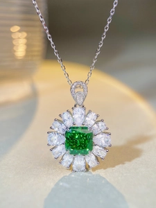 Makroaufnahme eines smaragdgrünen Anhängers mit Birnenschliff-Diamanten auf Silberkette