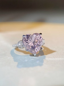 Macro d'une bague en argent S925 avec une pierre rose en forme de cœur et des pierres latérales